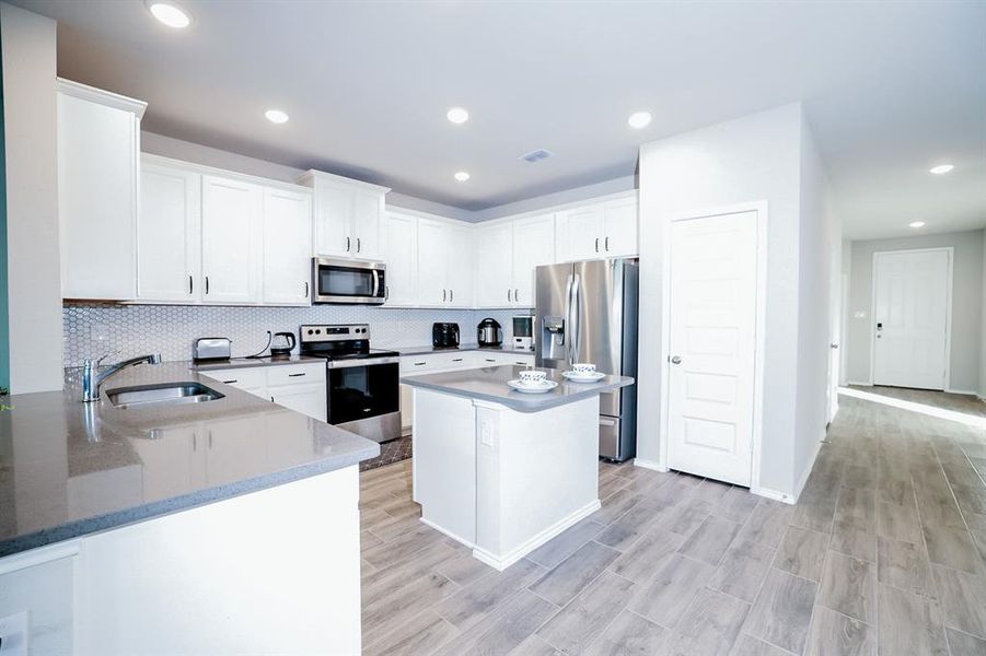 Kitchen with stainless steel appliances, white cabinetry, dark stone counters, and sink