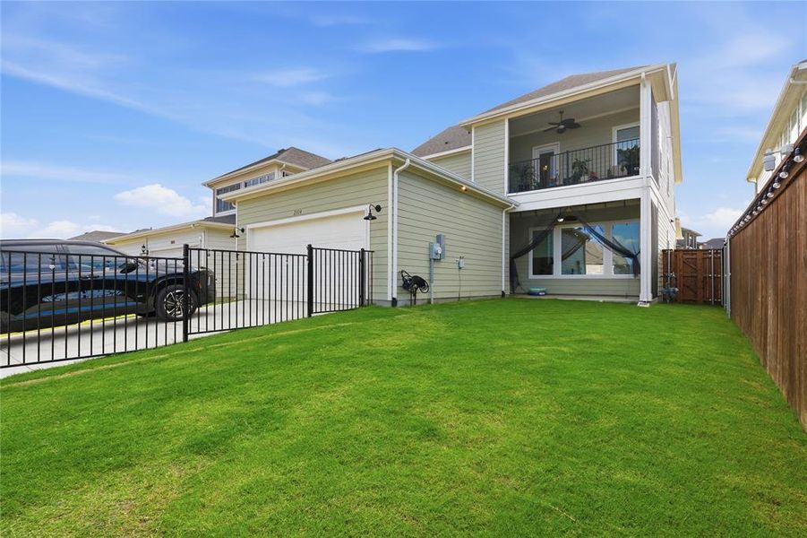Spacious backyard featuring a two-story residence with a second-level balcony, a covered patio, and a wooden privacy fence Spacious backyard featuring a two-story residence with a second-level balcony, a covered patio, and a wooden privacy fence