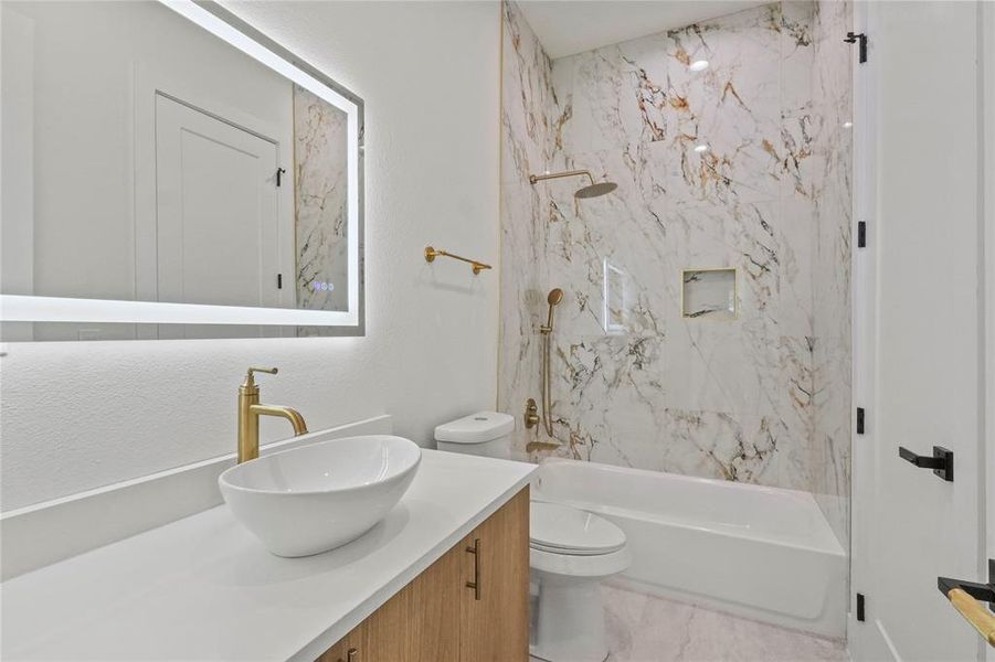 Full bathroom with tile patterned flooring, tiled shower / bath, toilet, and vanity