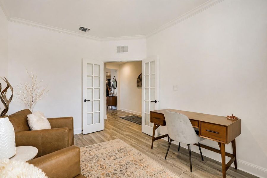 Elegant French doors open to a versatile study with crown molding and sleek wood flooring. Elegant French doors open to a versatile study with crown molding and sleek wood flooring.