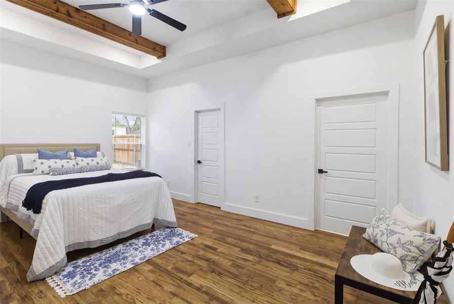 Bedroom featuring wood-finish flooring, a tray ceiling with exposed wood beams, and a ceiling fan