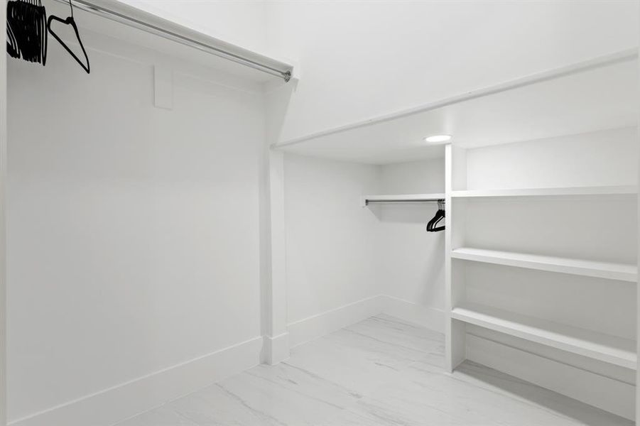 Walk in closet featuring light marble finish floors