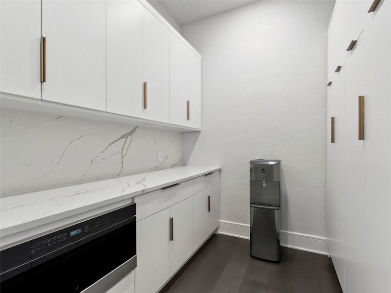 Pantry featuring custom cabinets and built in microwave