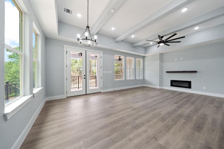 Spacious living area featuring wood-finish flooring, high vaulted ceilings with exposed beams, and recessed lighting