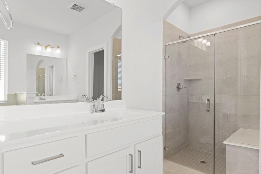 This beautifully designed vanity area offers dual sinks, plenty of storage, and crisp white cabinetry. Just steps away, the large walk-in shower features elegant tile surrounds and a sleek glass enclosure—perfect for a refreshing start to your morning!