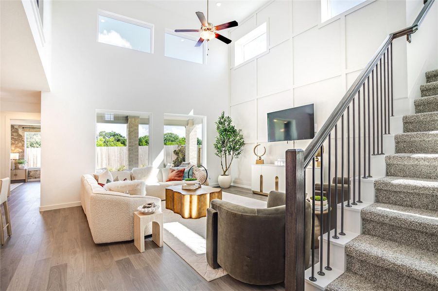 The spacious living room features high ceilings and abundant natural light from large windows. It includes a cozy seating area, modern decor, and an open staircase with stylish railing. Perfect for entertaining and relaxation. The spacious living room features high ceilings and abundant natural light from large windows. It includes a cozy seating area, modern decor, and an open staircase with stylish railing. Perfect for entertaining and relaxation.