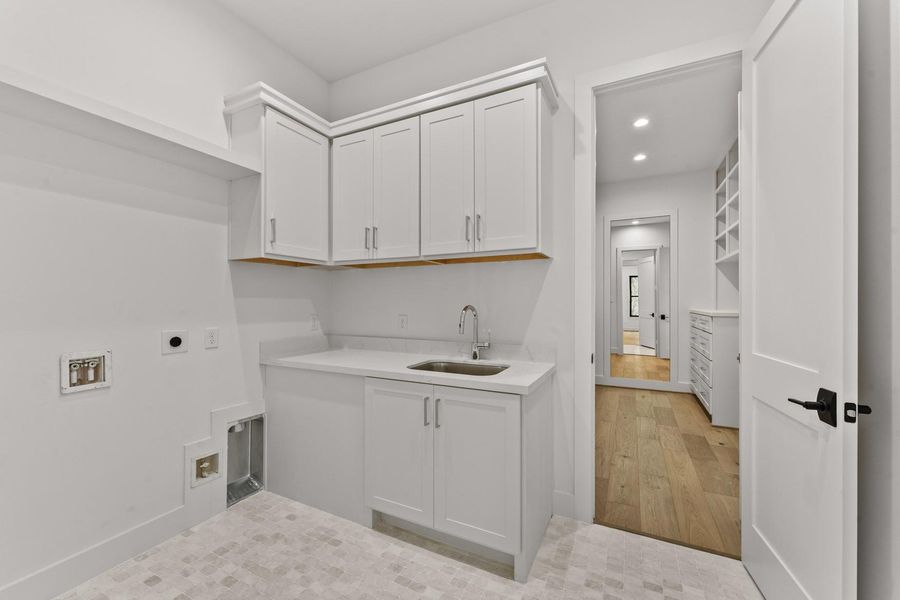 Utility room with sink and storage, connecting to one of the two primary closets