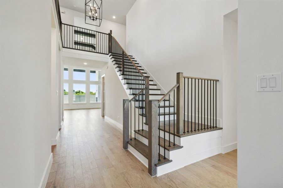 Grand entryway featuring a two-story staircase with dark wood-finish treads and risers, black metal balusters, and a matching wood-finish handrail Grand entryway featuring a two-story staircase with dark wood-finish treads and risers, black metal balusters, and a matching wood-finish handrail