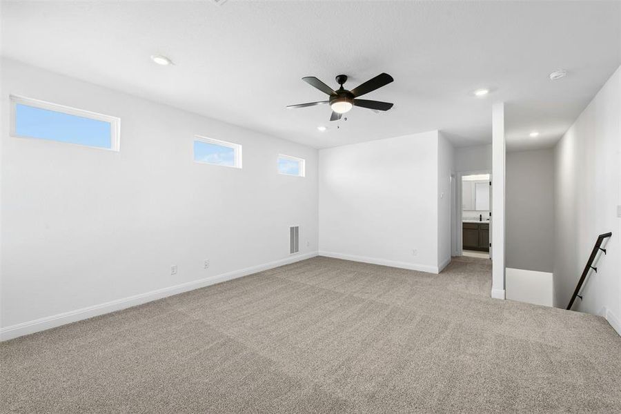 Spacious carpeted room featuring a ceiling fan with integrated lighting, recessed lighting, and three horizontal windows