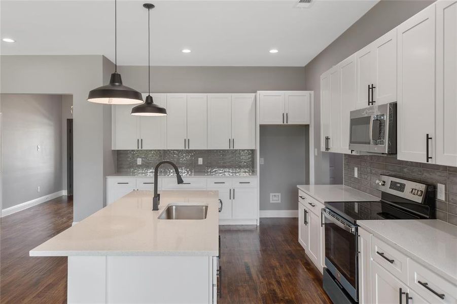 Kitchen with sink, pendant lighting, white cabinetry, and appliances with stainless steel finishes