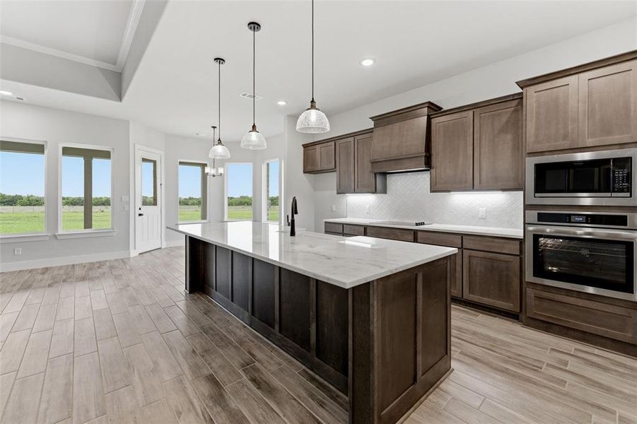 Kitchen featuring an expansive island with a light-toned countertop, wood-finish flooring, recessed lighting, and stainless steel appliances