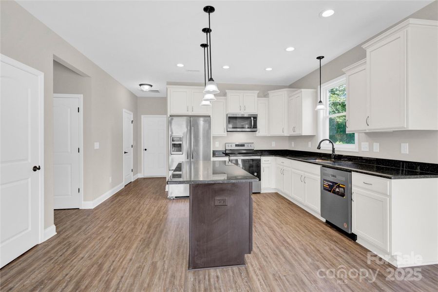 Kitchen with island, granite, white cabinetry.