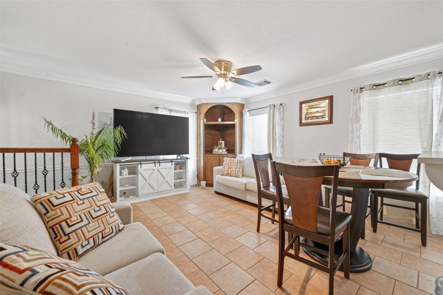Second-level living and dining area with open layout, ceiling fan, and abundant natural light.