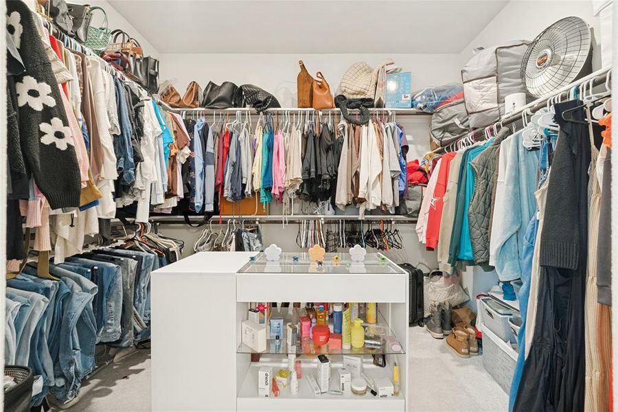 Spacious walk-in closet featuring white wire shelving, multiple hanging rods, and a central white island with glass display shelves