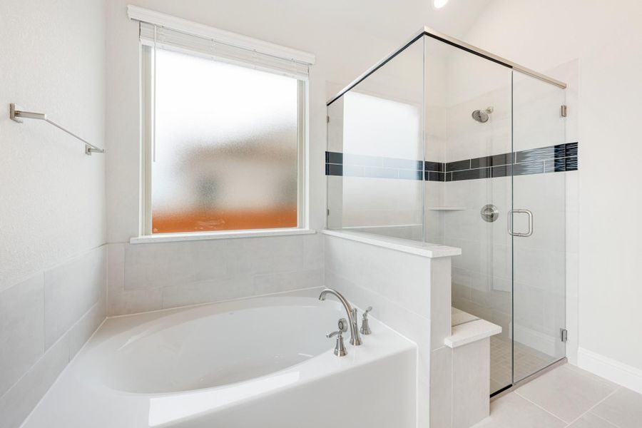White bathroom with soaking tub, glass-enclosed shower, and frosted window