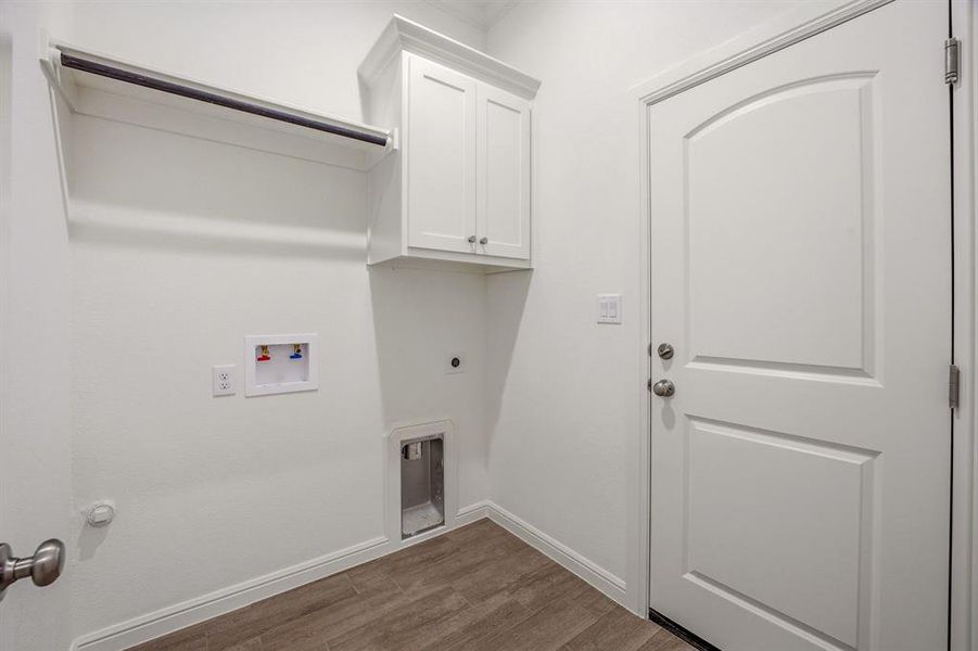 This utility area features ample storage with white cabinetry and an open shelf with a hanging rod