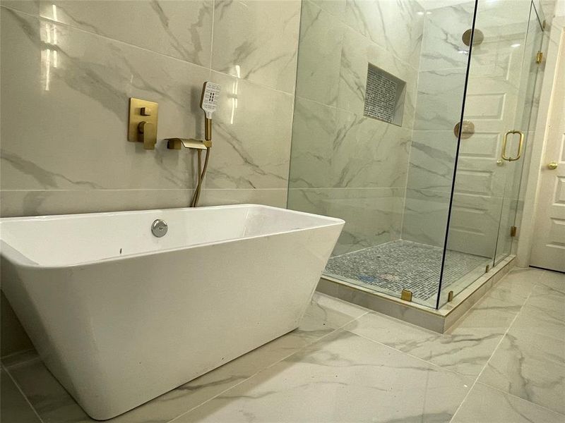 Bathroom with tile floors, shower with separate bathtub, and tile walls