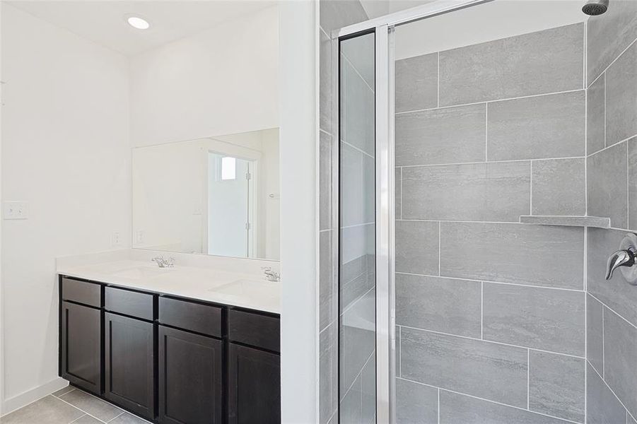 Bathroom featuring vanity, tile patterned floors, and a shower with shower door