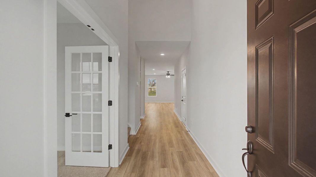 Entry to home with light LVP flooring and glass doors to study