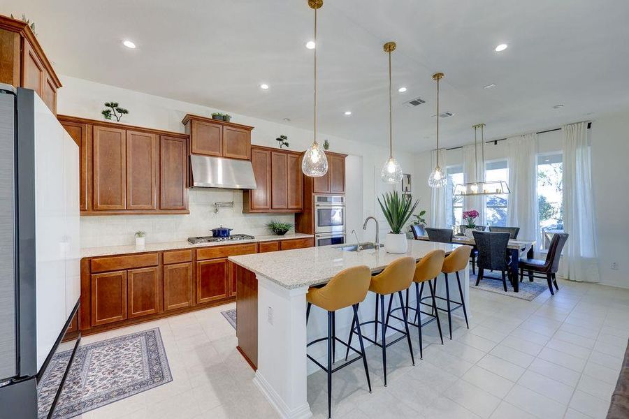 Kitchen featuring brown cabinetry, decorative backsplash, stainless steel appliances, recessed lighting, and light stone countertops