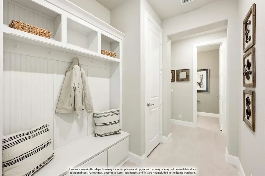 Mudroom with white built-in cubbies, coat hooks, bench seating, and upper storage shelves with baskets