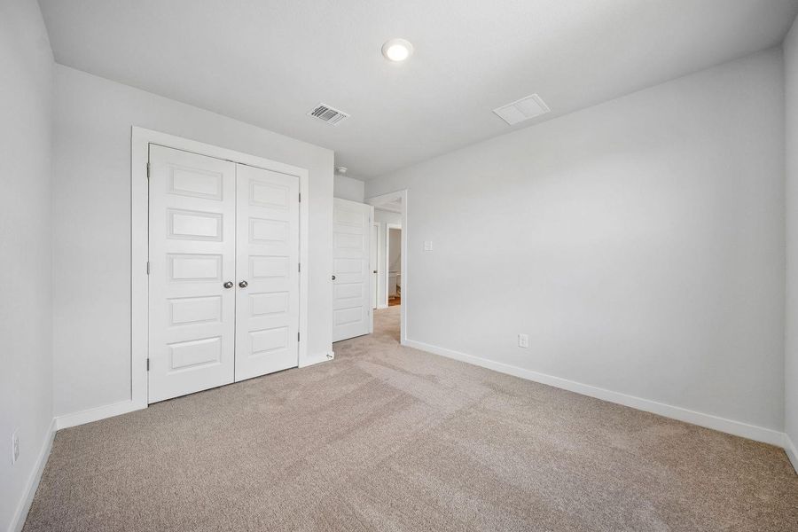 A well-lit bedroom featuring ample closet space and soft carpeting. A well-lit bedroom featuring ample closet space and soft carpeting.