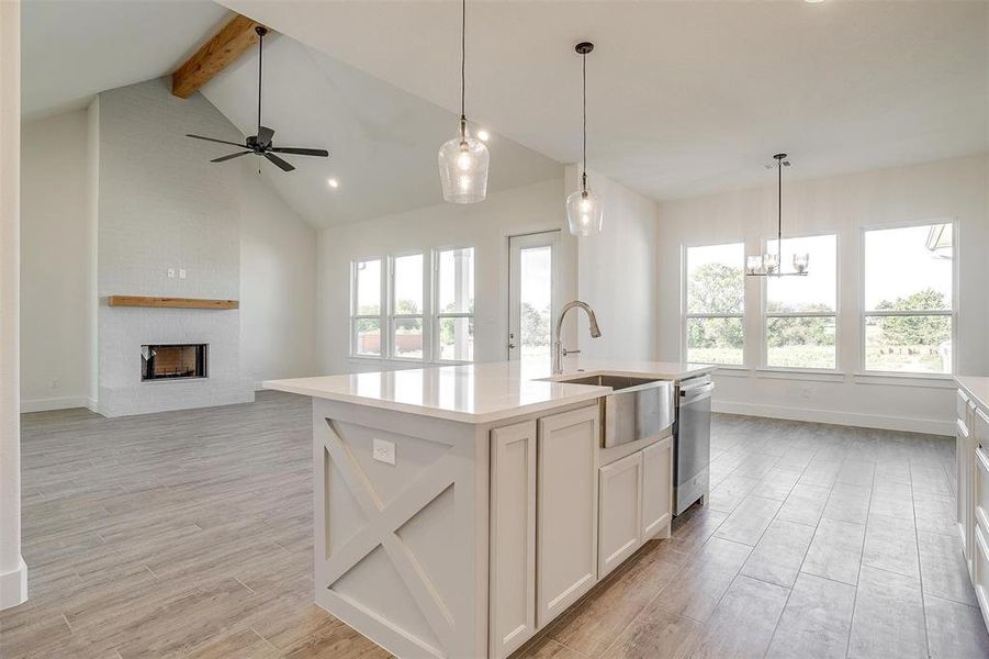 Kitchen with lofted ceiling with beams, dishwasher, light wood-type flooring, and a kitchen island with sink