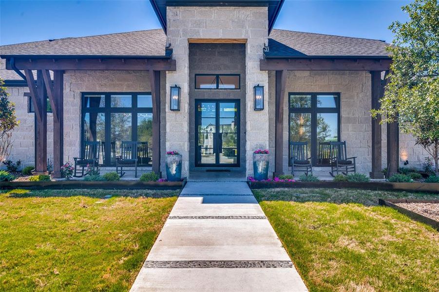 View of exterior entry featuring french doors and a lawn