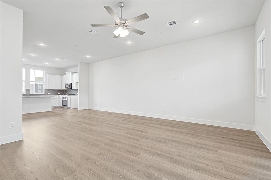 Spacious open concept living area featuring light-toned flooring, recessed lighting, and a ceiling fan