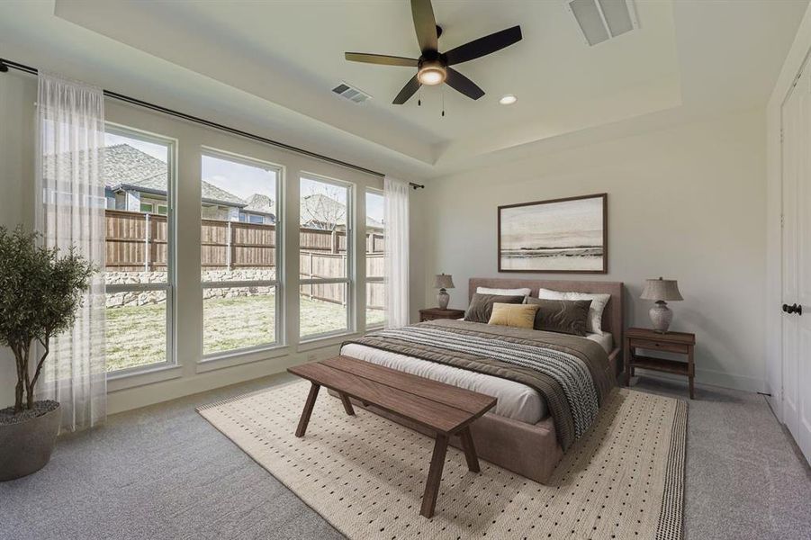 Virtually staged photo - Bedroom with a raised ceiling, light colored carpet, a ceiling fan, and recessed lighting