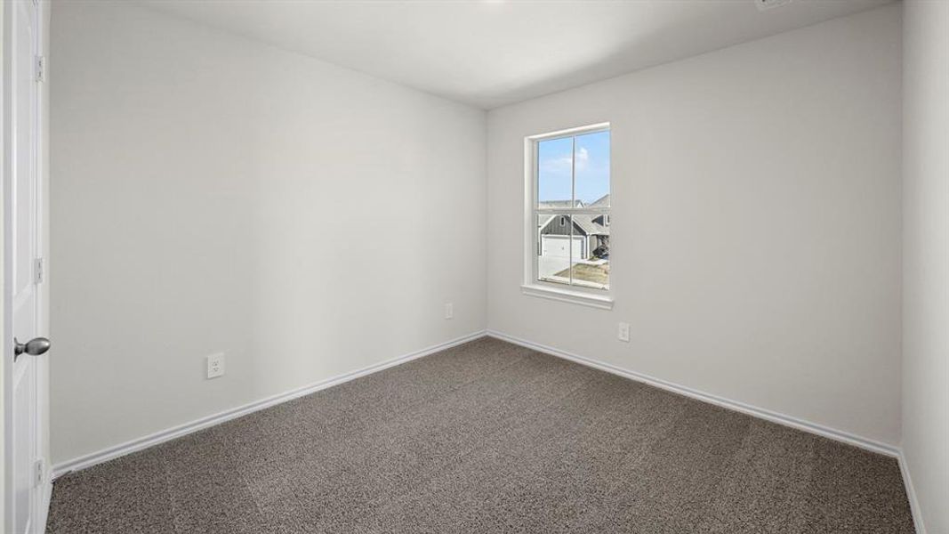 Empty room featuring dark colored carpet and baseboards