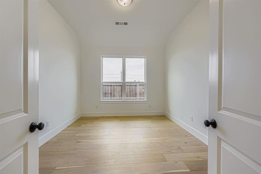 Spare room featuring light wood-type flooring and lofted ceiling Spare room featuring light wood-type flooring and lofted ceiling