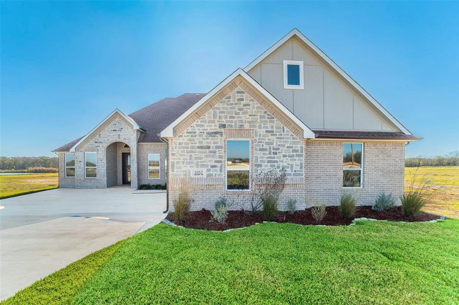 View of front of property with a front lawn, board and batten siding, and brick siding View of front of property with a front lawn, board and batten siding, and brick siding