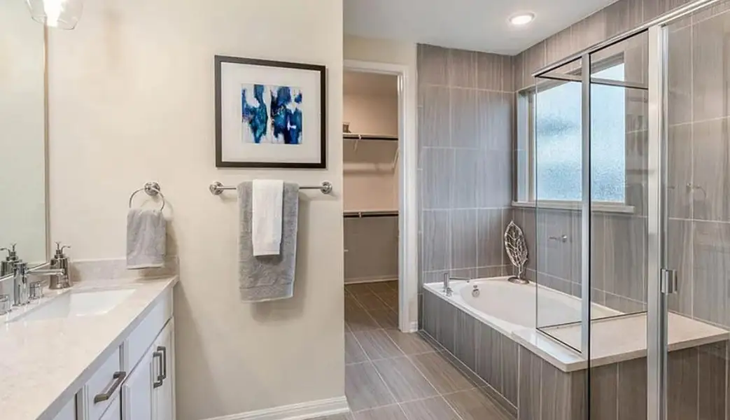 Full bath with vanity, a stall shower, a bath, and a spacious closet