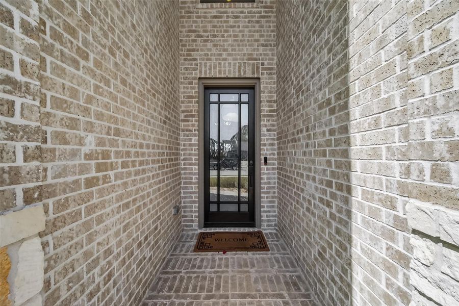 This photo shows a welcoming entryway with a brick exterior, featuring a modern glass-paneled door, providing a charming first impression for visitors.