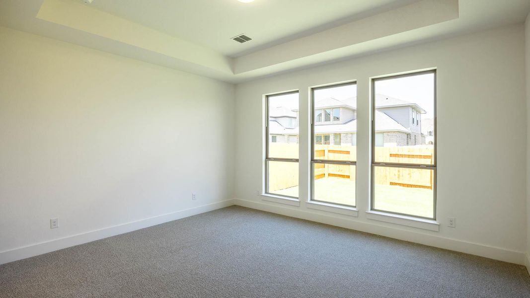 Spare room featuring light colored carpet and a tray ceiling Spare room featuring light colored carpet and a tray ceiling