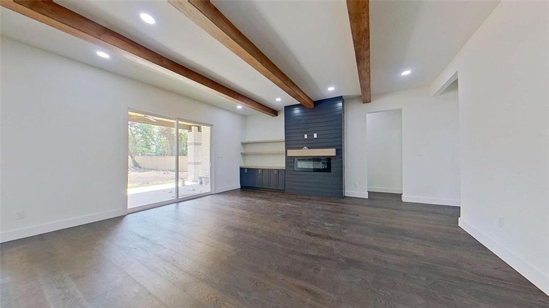 Unfurnished living room featuring beamed ceiling, a large fireplace, dark wood-style flooring, and recessed lighting