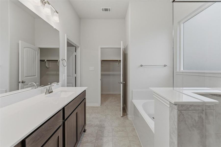 Bathroom featuring a dual-sink vanity with white countertop, dark wood-finish cabinetry, and brushed nickel fixtures