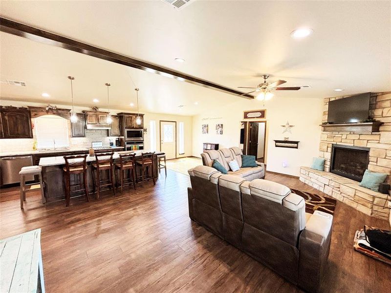 Living area with Luxury vinyl plank flooring, a ceiling fan, a stone fireplace, and recessed lighting Living area with Luxury vinyl plank flooring, a ceiling fan, a stone fireplace, and recessed lighting