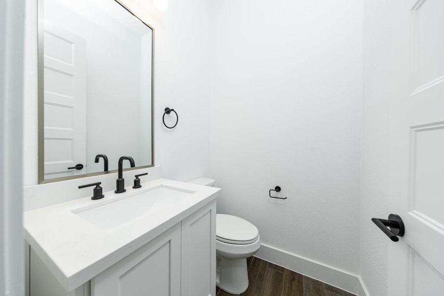 The powder bath features a stylish vanity with framed mirror, and a clean, modern design.