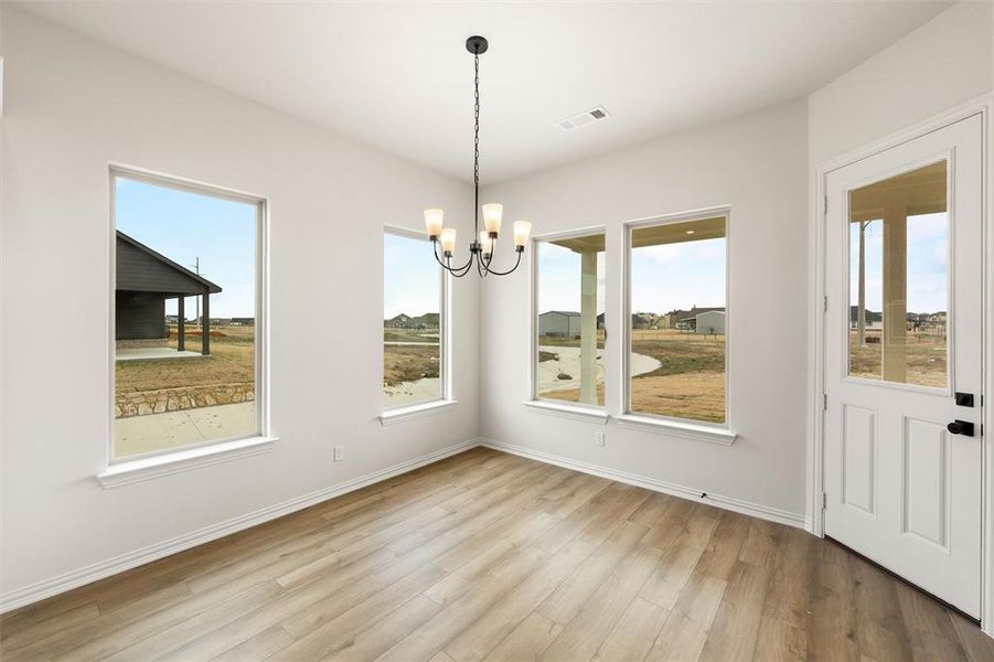 Unfurnished dining area featuring hanging lights and light wood finished floors