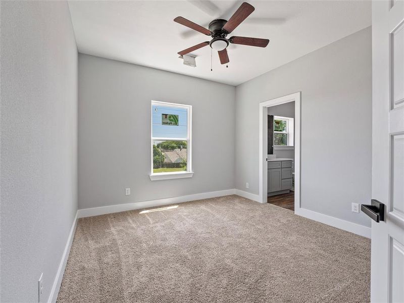 Empty room featuring dark carpet, a ceiling fan, and baseboards