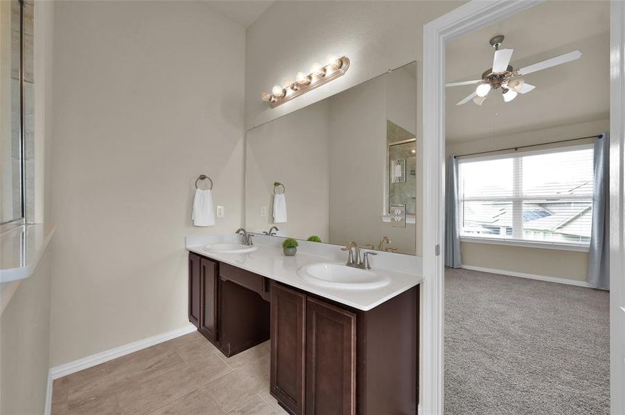 This is a spacious bathroom featuring dual vanity sinks with a large mirror, tile flooring, and ample natural lighting.