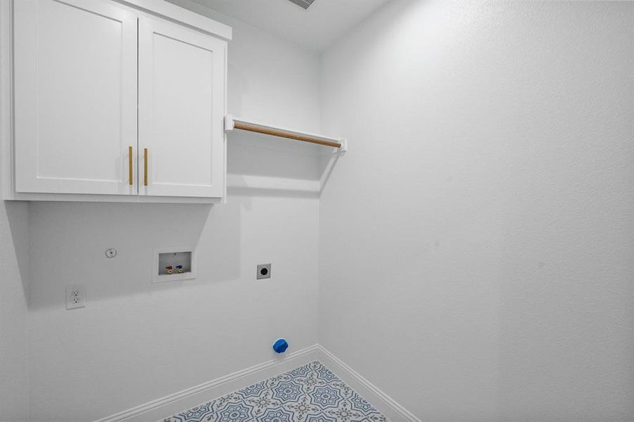 Clothes washing area with washer hookup, cabinet space, hookup for an electric dryer, gas dryer hookup, and baseboards