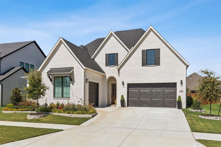 View of front of property featuring a front lawn and a garage