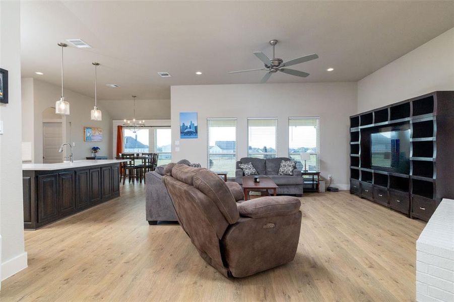 Living room with healthy amount of natural light, light wood-style floors, recessed lighting, a chandelier, and ceiling fan