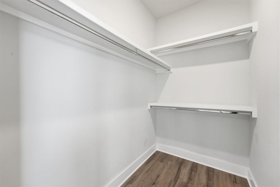 Spacious walk-in closet featuring built-in shelving and dual hanging rods, offering ample and well-organized storage space in a clean, modern design.