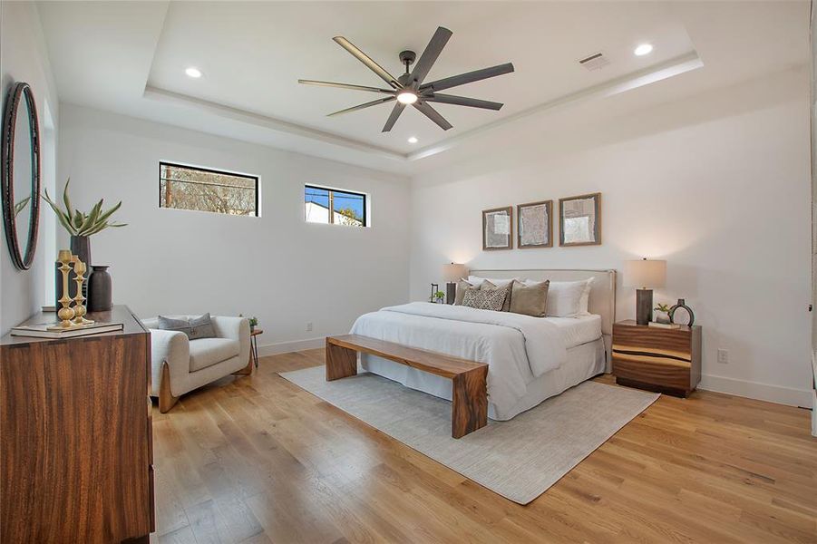 Bedroom featuring a tray ceiling, light hardwood / wood-style flooring, and ceiling fan