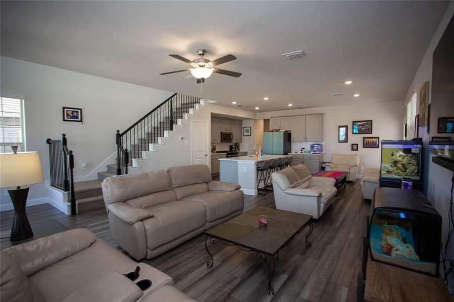 Living area featuring visible vents, stairs, recessed lighting, a ceiling fan, and dark wood-style flooring