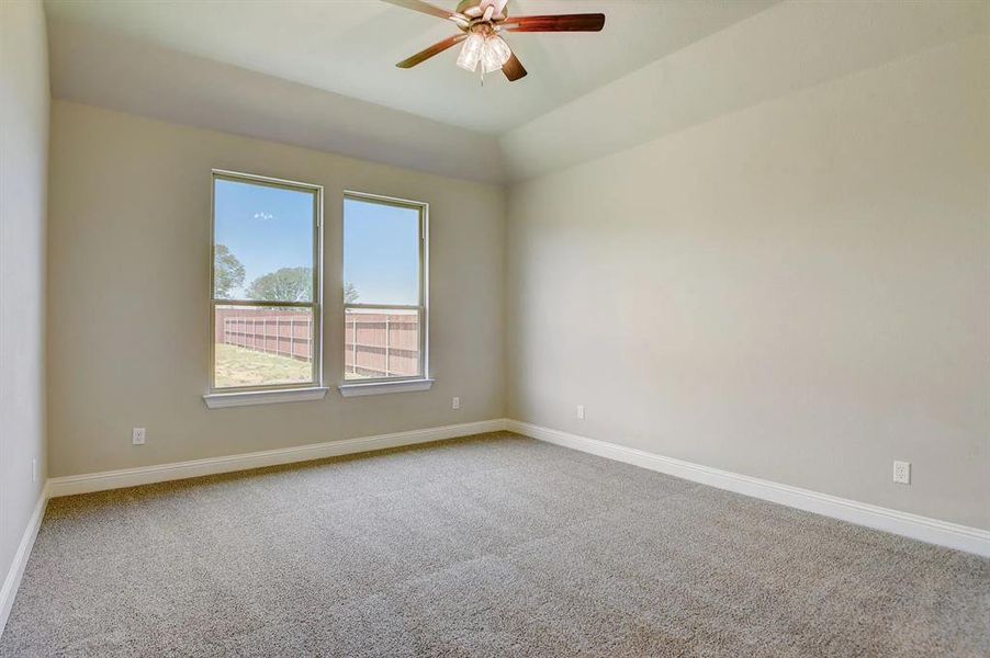 Carpeted spare room featuring a ceiling fan and baseboards